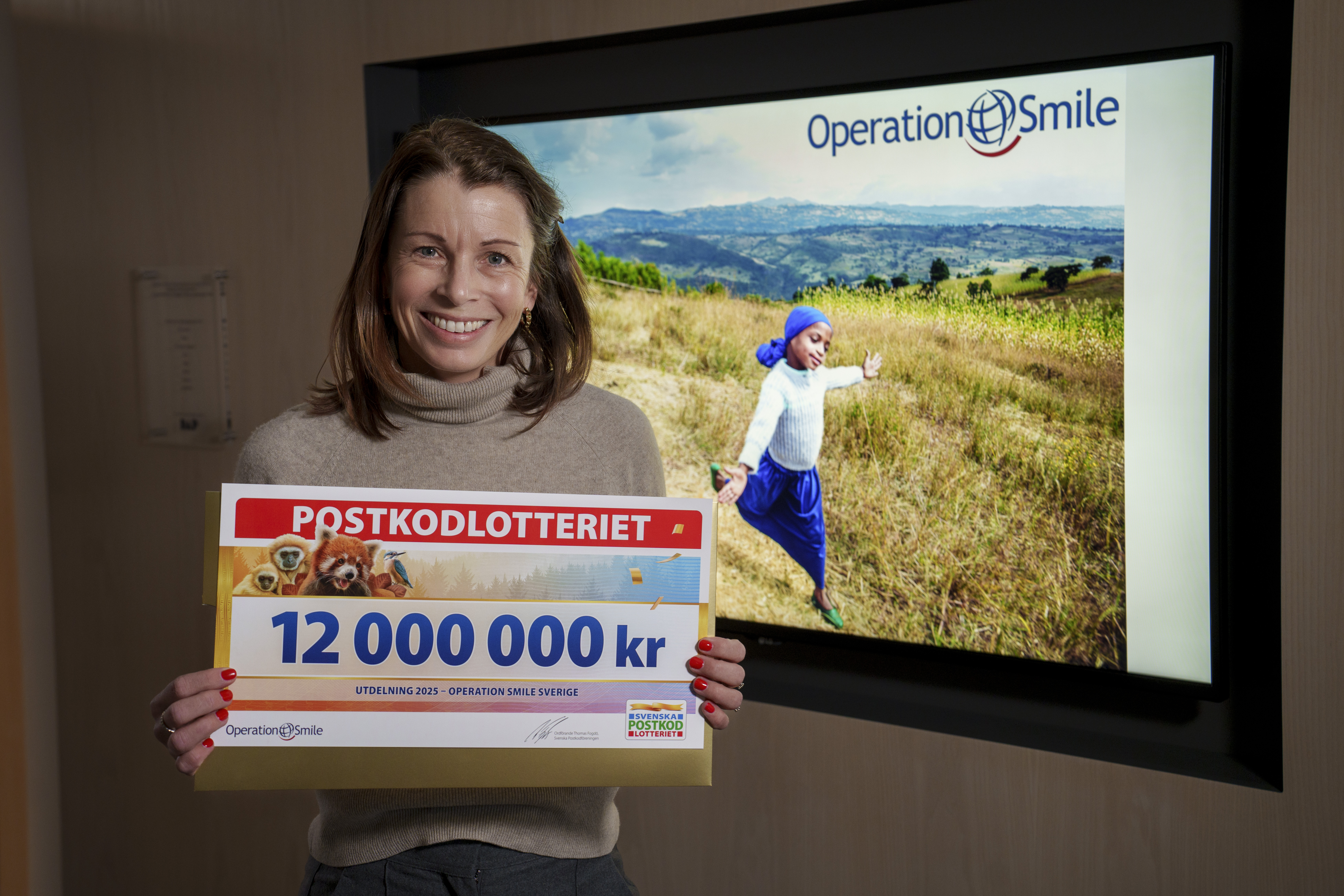 Operation Smile Sveriges generalsekreterare Malin Söderström håller upp en check på 12 miljoner kronor.
